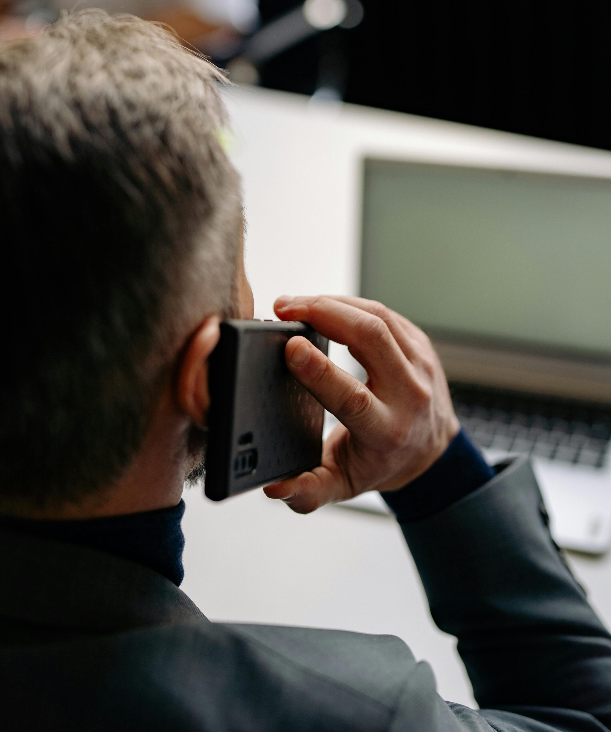 Businessman making a phone call while working on a laptop at the office.